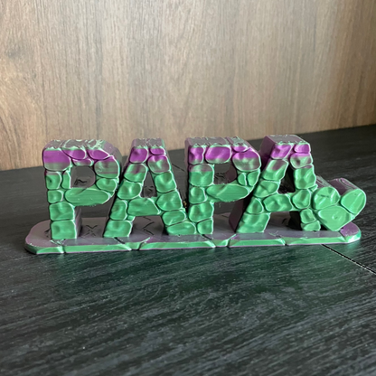 3D-gedruckter Schriftzug „PAPA" in Grün/Violett mit Stein-Optik-Textur