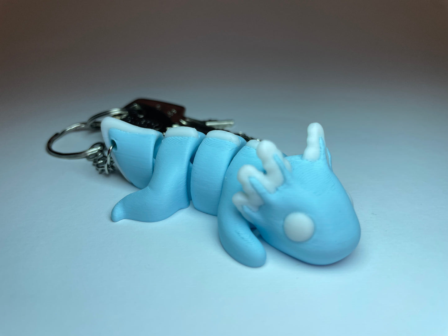 Hellblauer Flexi-Axolotl Schlüsselanhänger mit weißen Kiemen aus 3D-Druck