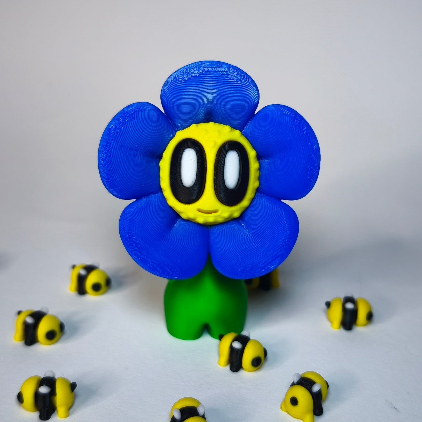 3D-gedruckte Blume ‚Daisy‘ mit Gesicht im Gänseblümchen-Stil in blau als Dekofigur