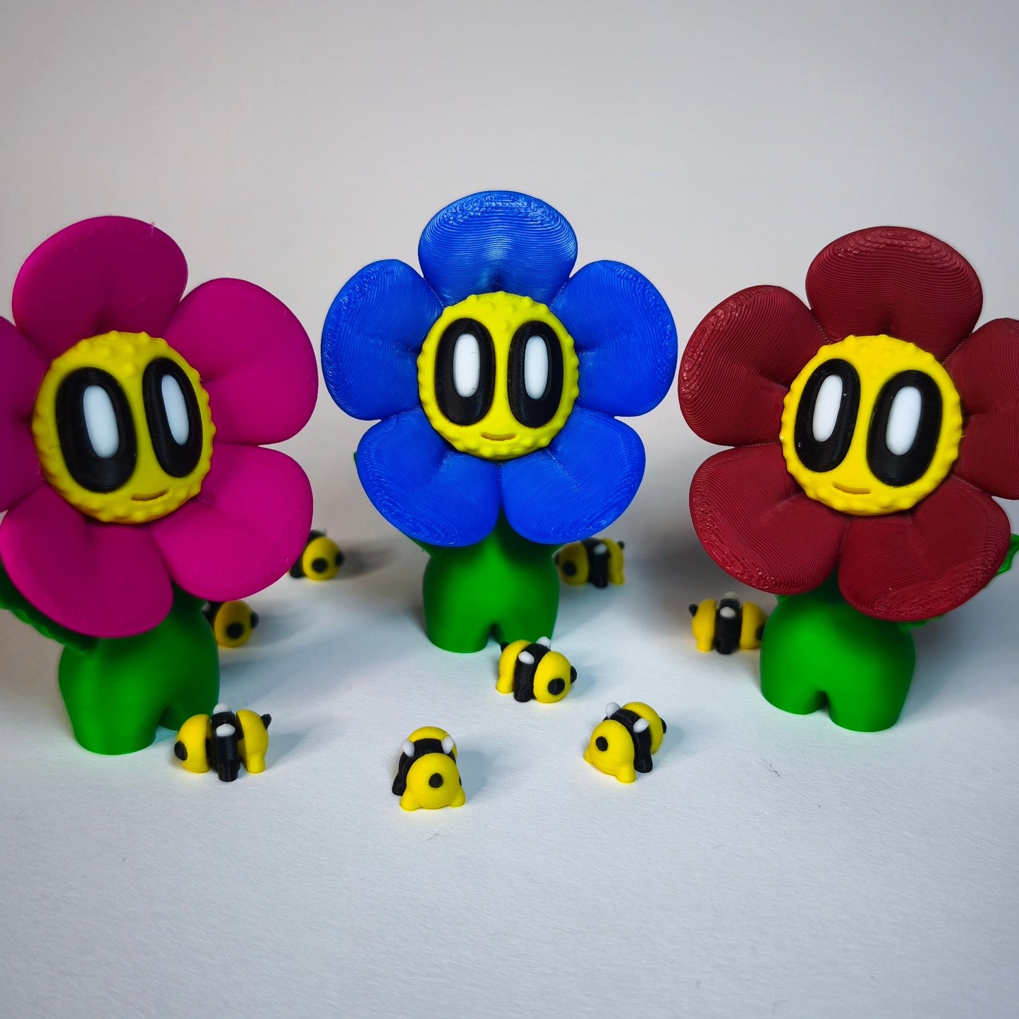 3D-gedruckte Blume ‚Daisy‘ mit Gesicht im Gänseblümchen-Stil in magenta, blau und rot als Dekofigur