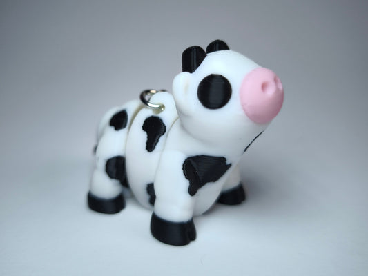 Linda die Flexi-Kuh – beweglicher 3D-gedruckter Schlüsselanhänger in Schwarz-Weiß mit rosa Schnauze.