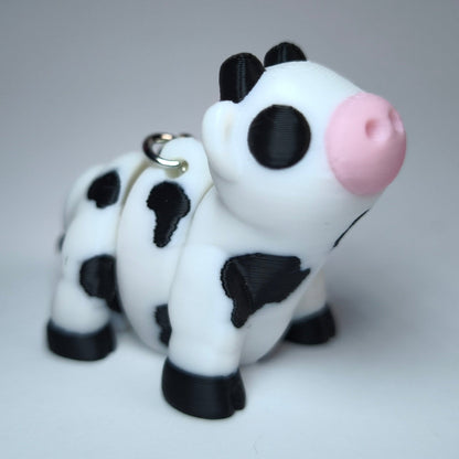 Linda die Flexi-Kuh – beweglicher 3D-gedruckter Schlüsselanhänger in Schwarz-Weiß mit rosa Schnauze.