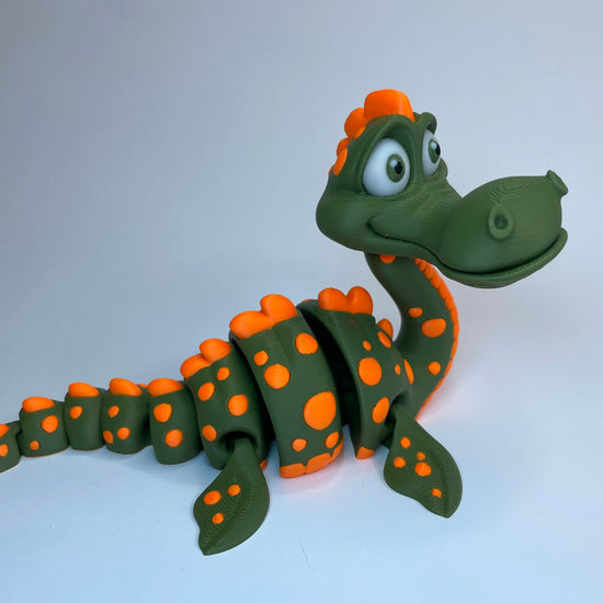 Produktvideo von Günter – dem freundlichen Loch Ness Monster: Vier 3D-gedruckte Figuren stehen nebeneinander, eine wird in die Hand genommen, bewegt und von allen Seiten gezeigt. Die Flexi-Figur aus PLA ist beweglich, handgemacht im Allgäu und nachhaltig produziert von 3DruckAS.