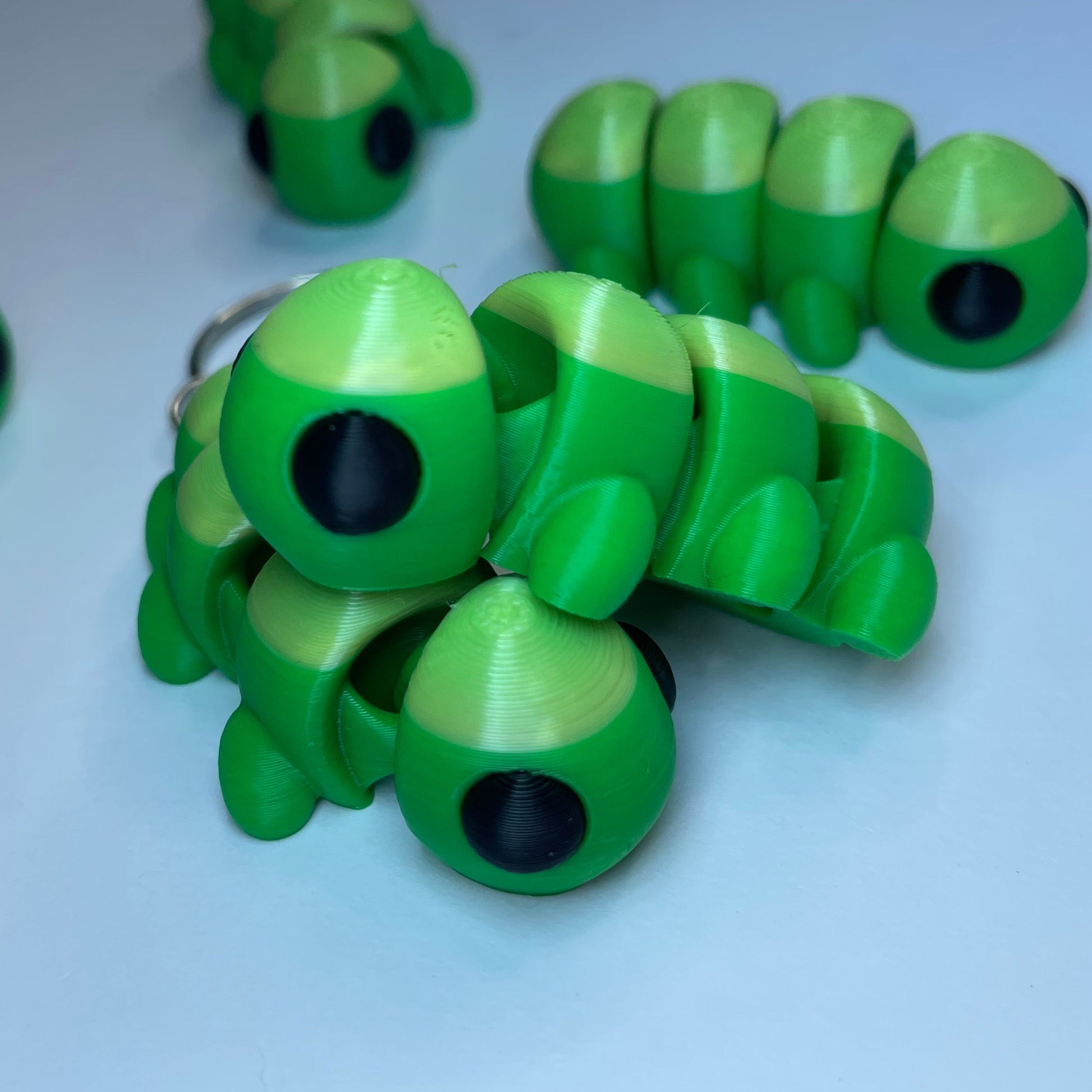 Flexi-Tierfigur Raupe Raupy – Schlüsselanhänger aus PLA, 3D-Druck, grün mit großen Augen.