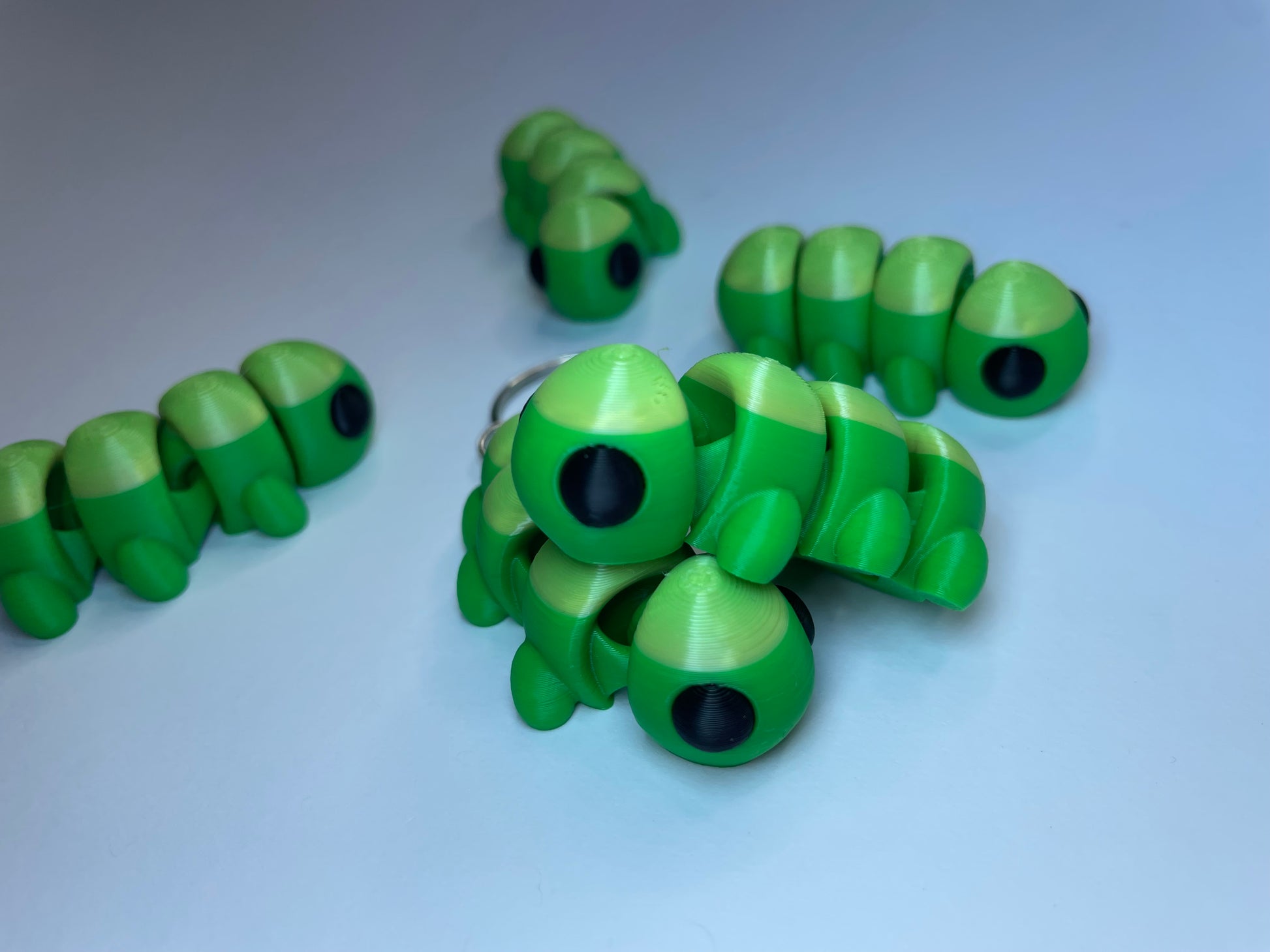 Flexi-Tierfigur Raupe Raupy – Schlüsselanhänger aus PLA, 3D-Druck, grün mit großen Augen.
