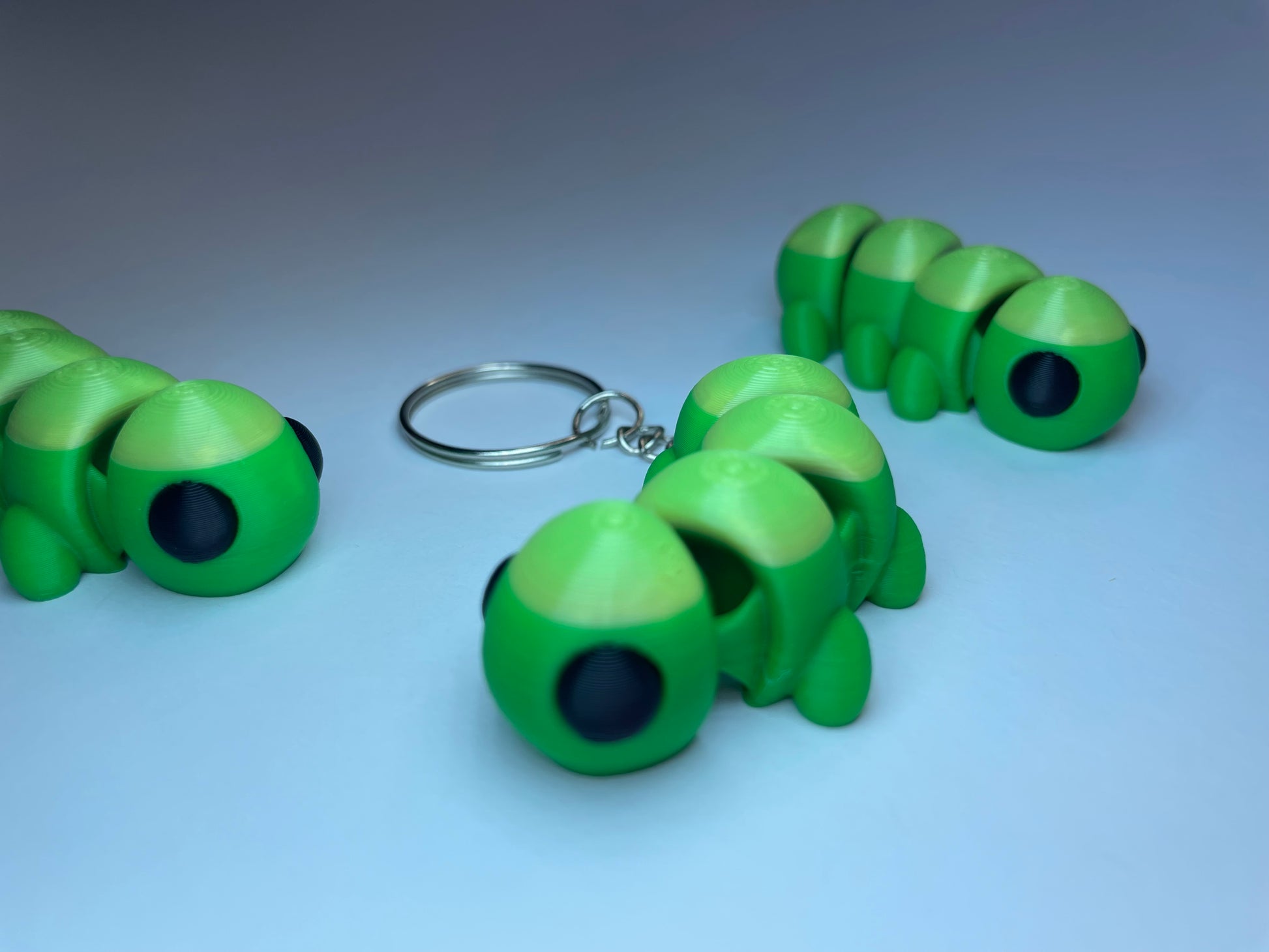 Flexi-Tierfigur Raupe Raupy – 3D-Schlüsselanhänger aus PLA, grün mit großen Augen.